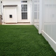 artificial turf installed along white fence in backyard